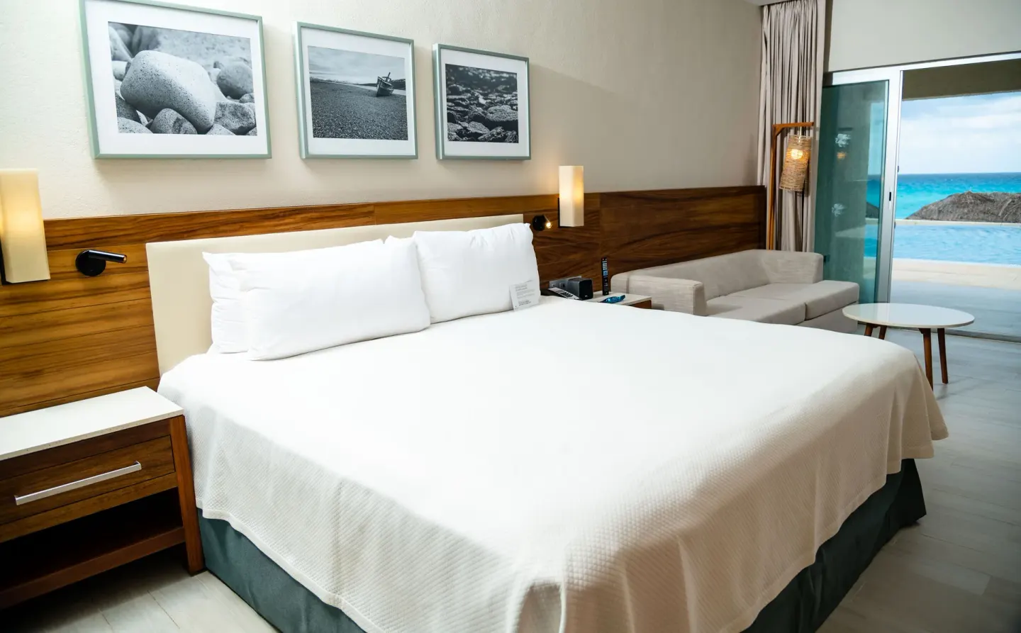 King bed and sofa in a Swim Up Oceanfront room at Emporio Cancun with ocean visible through terrace doors.