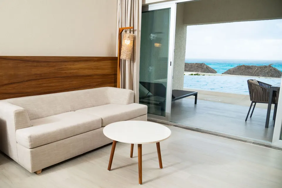 Sitting area in a Swim Up Oceanfront room at Emporio Cancun with sofa, table, terrace, and ocean view.