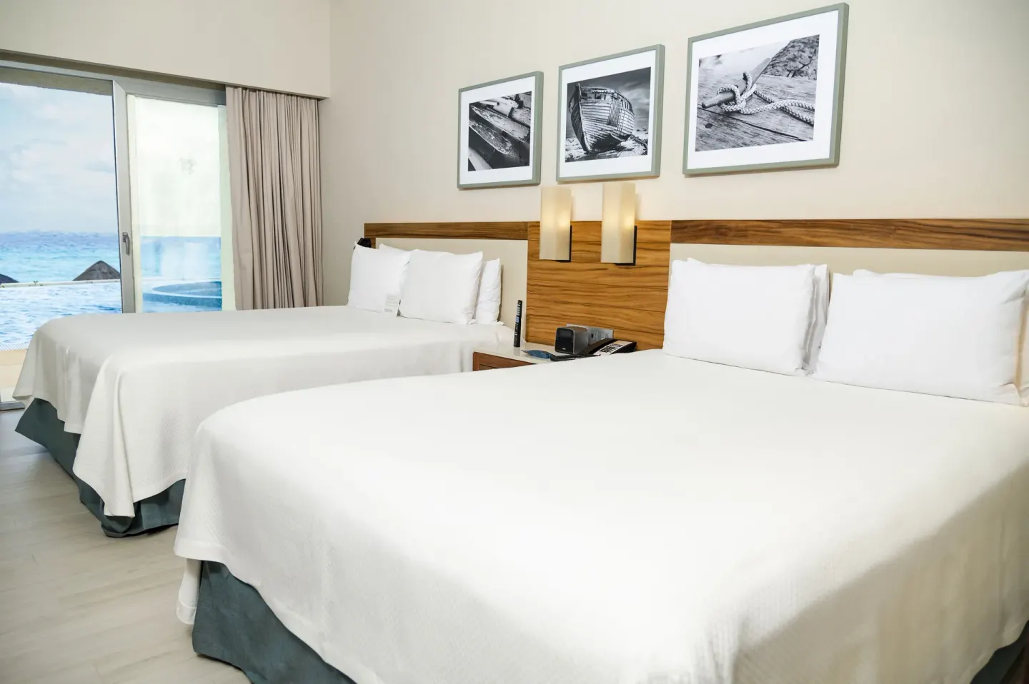 Two white beds in a Swim Up Oceanfront room at Emporio Cancun with ocean visible through sliding doors.