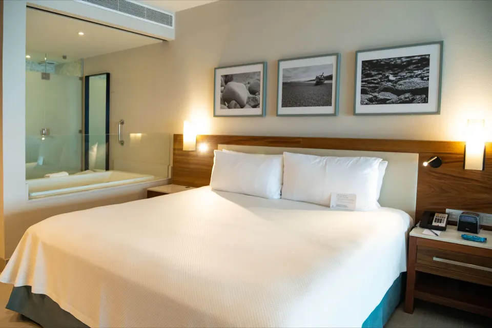 Swim Up Oceanfront Only Adults king bed beside a glass bath area at Emporio Cancun.