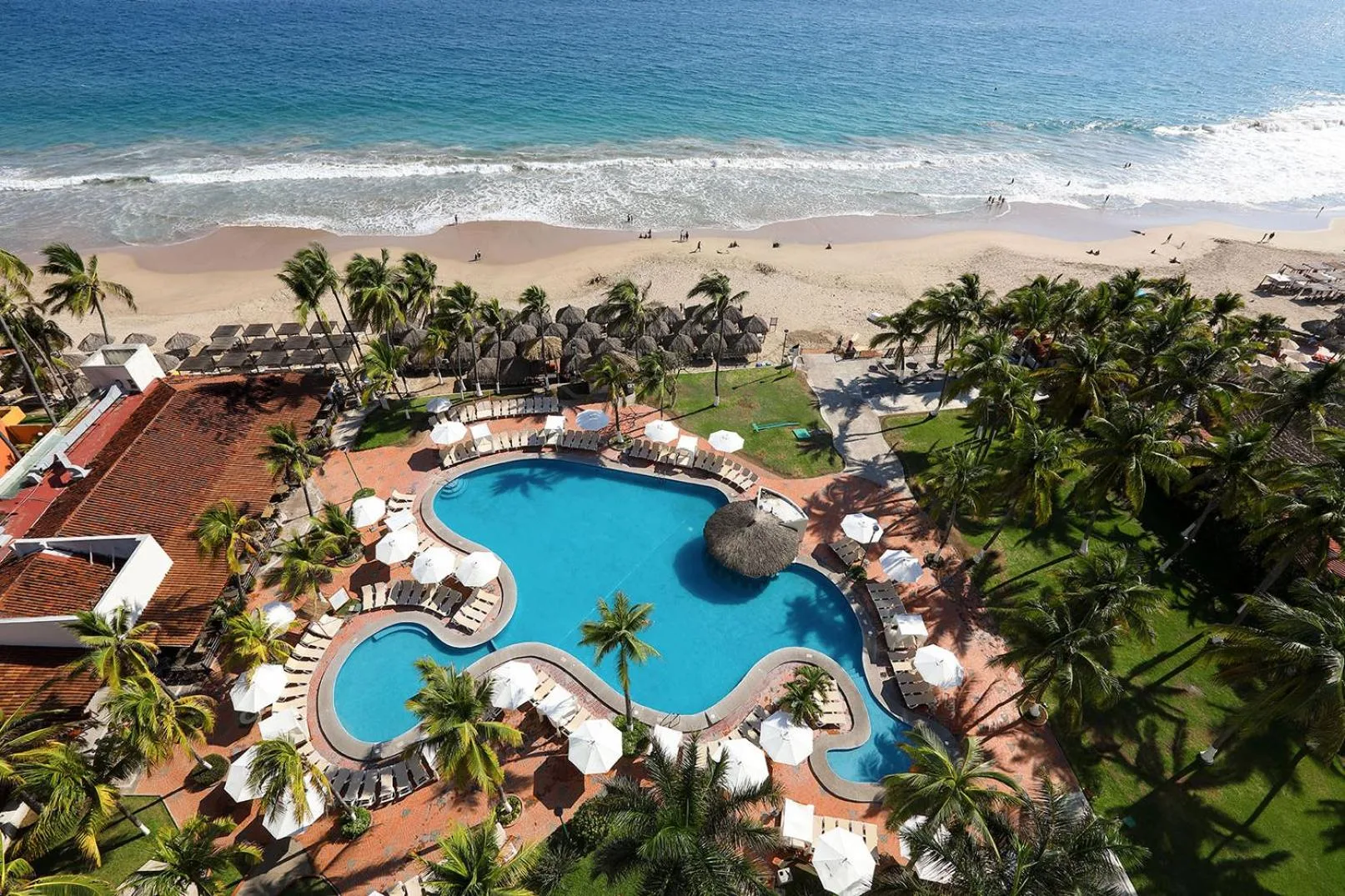 Aerial view of the beachfront pool, palms, and sandy shore at Emporio Ixtapa.