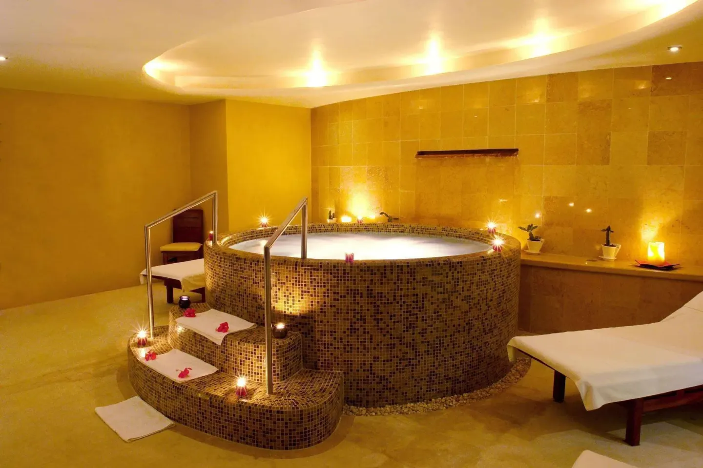 Candlelit spa tub with massage table in a warm tiled room at Emporio Ixtapa.