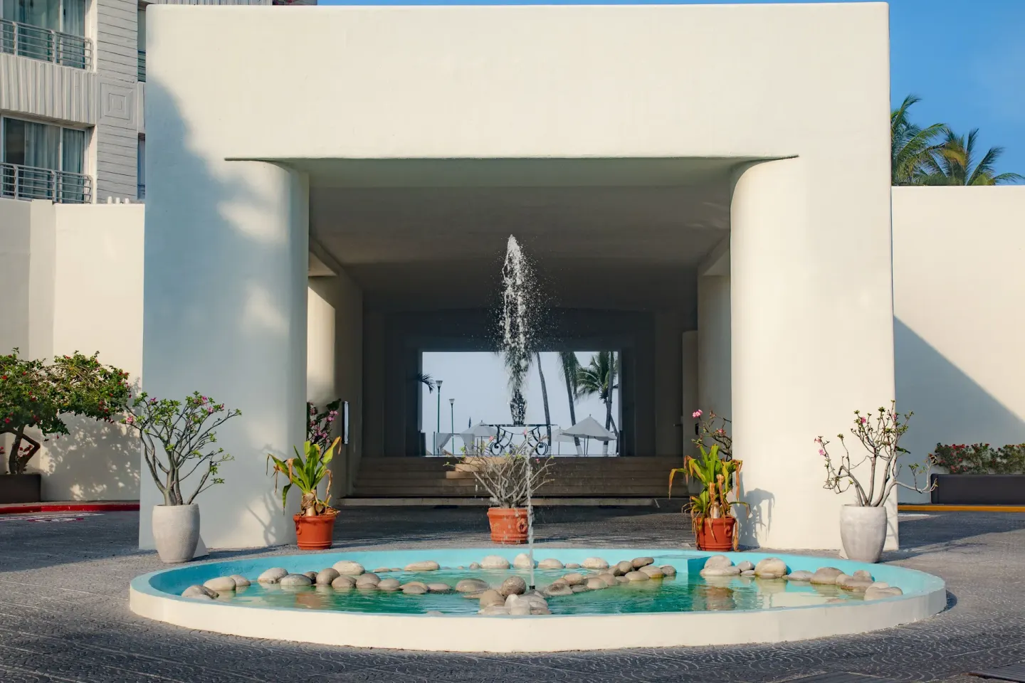 Entrance fountain framed by white columns and potted plants at Emporio Ixtapa.