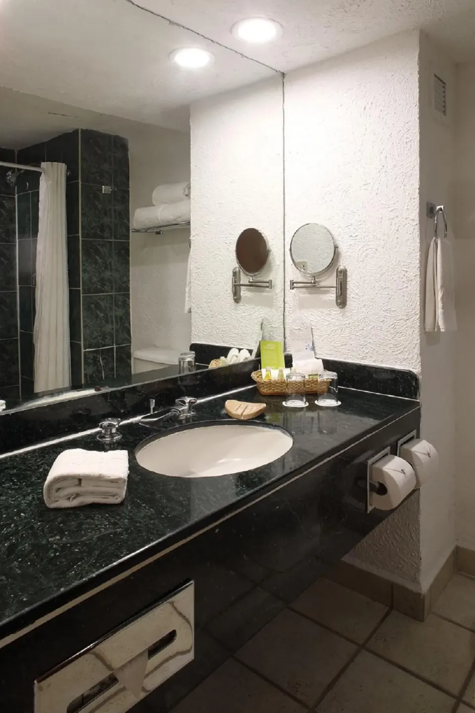 Guest bathroom with black vanity, sink, mirrors and shower at Emporio Ixtapa.