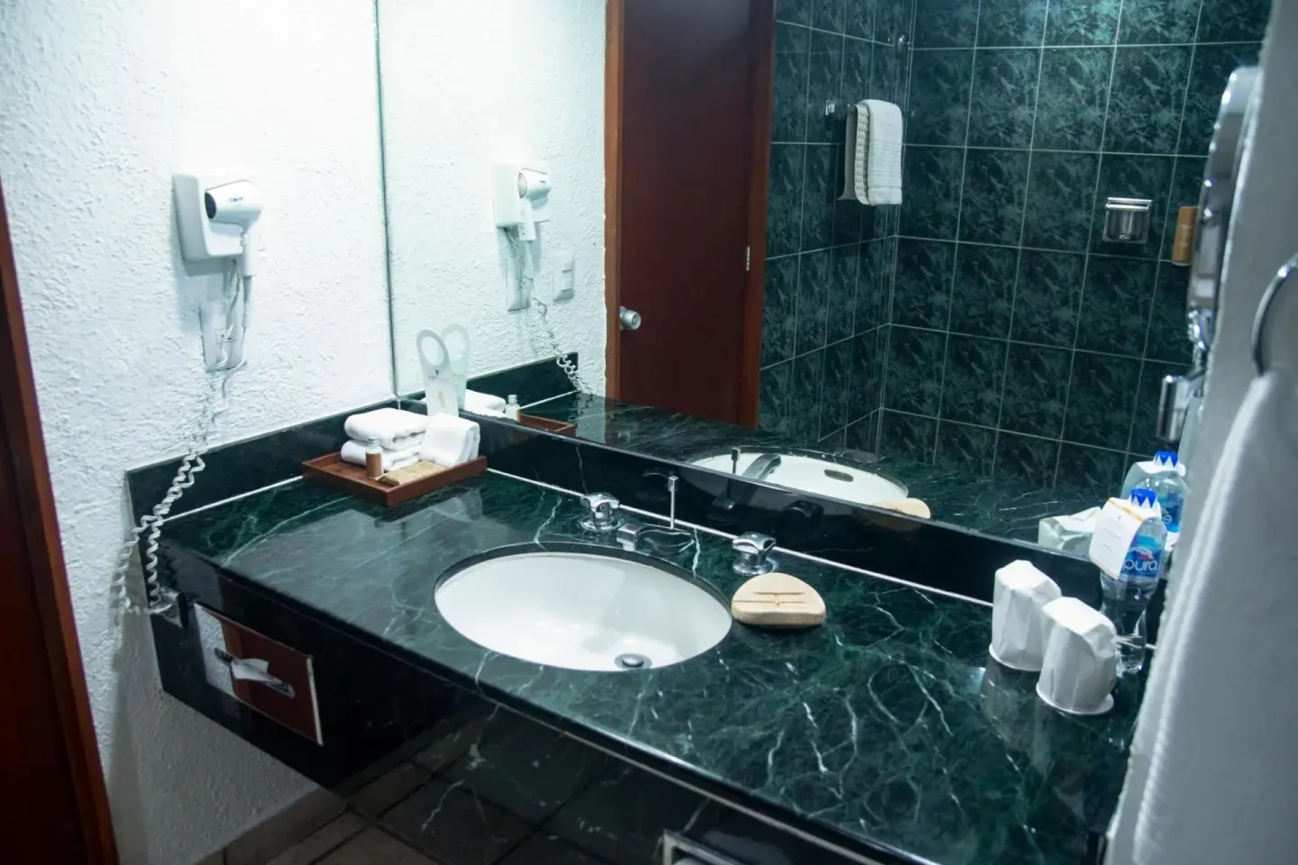 Guest bathroom with green marble vanity and mirrored wall at Emporio Ixtapa.