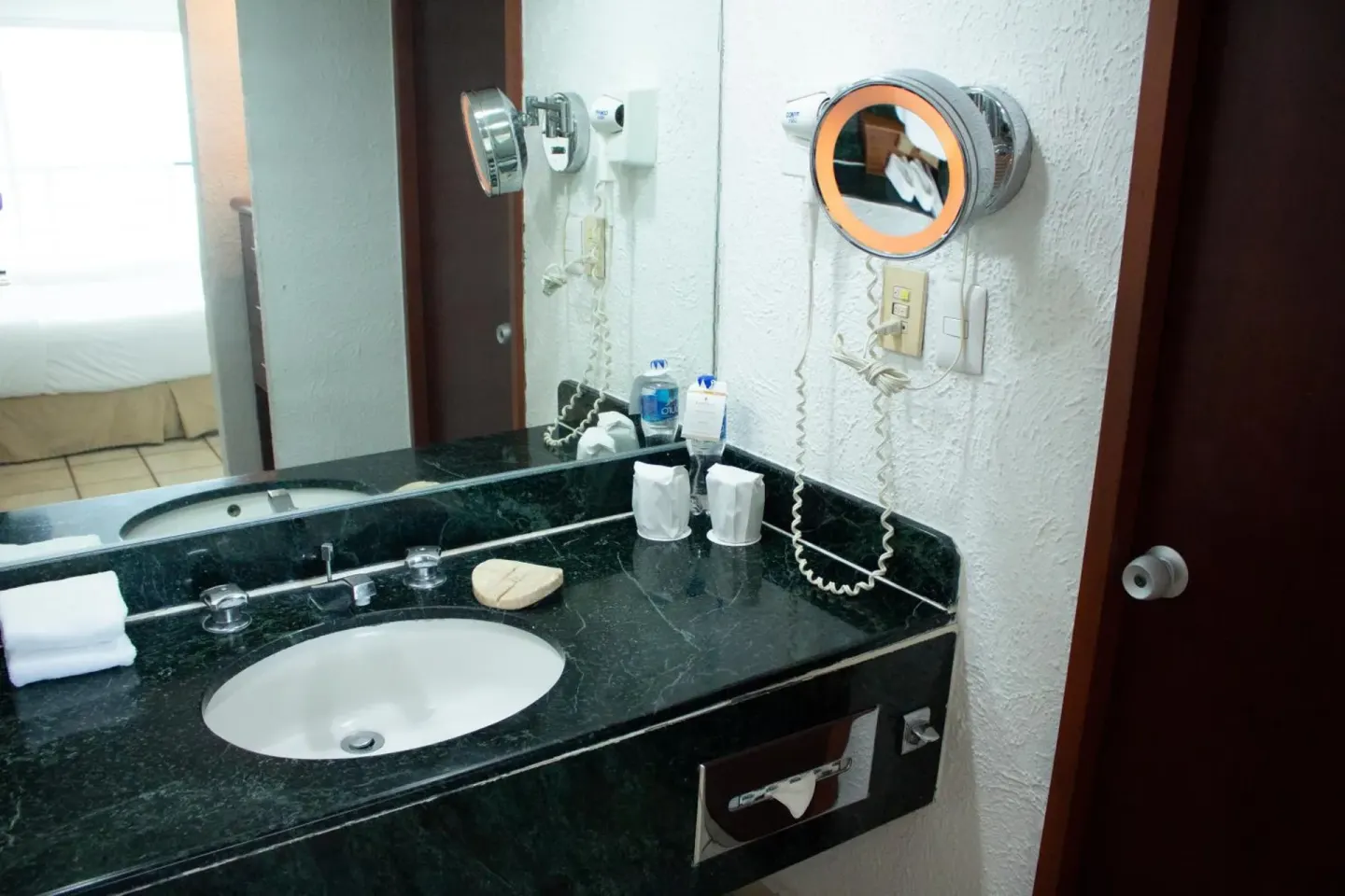 Guest bathroom vanity with sink, mirror, and wall-mounted makeup mirror at Emporio Ixtapa.
