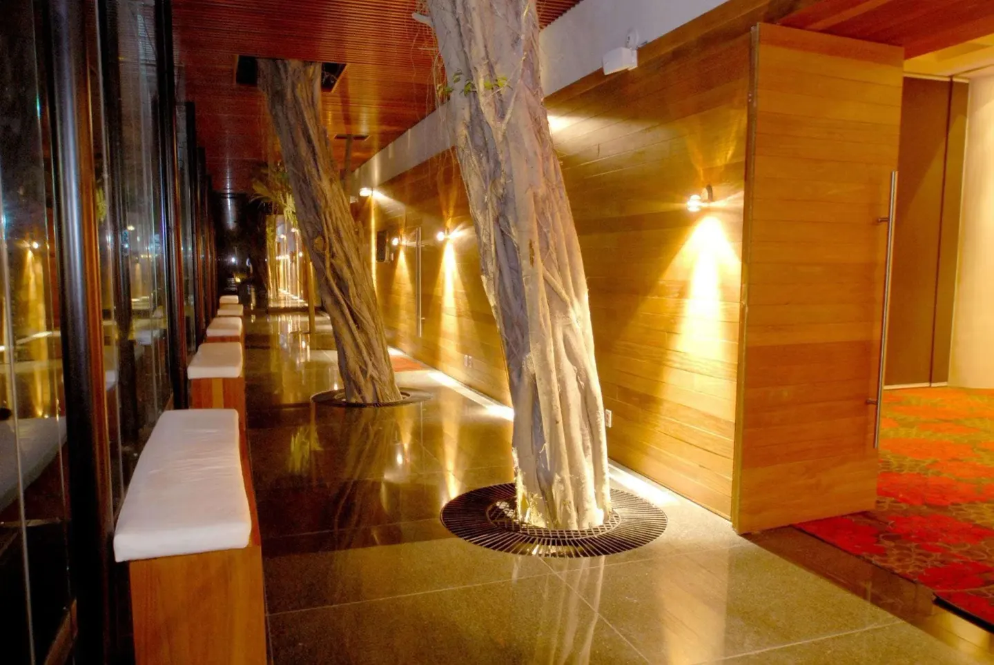 Interior corridor with tree trunks, wood paneling, and benches at Emporio Ixtapa.