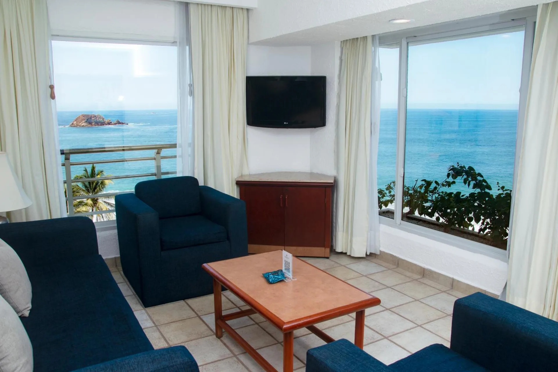 Ocean-view sitting area with blue seating and balcony at Emporio Ixtapa.