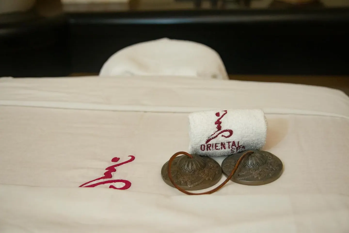 Spa linens, a rolled towel, and handheld cymbals arranged on a treatment bed at Emporio Ixtapa.