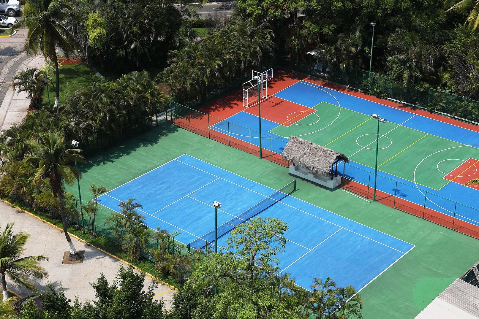 Aerial view of tennis and basketball courts surrounded by palms at Emporio Ixtapa.
