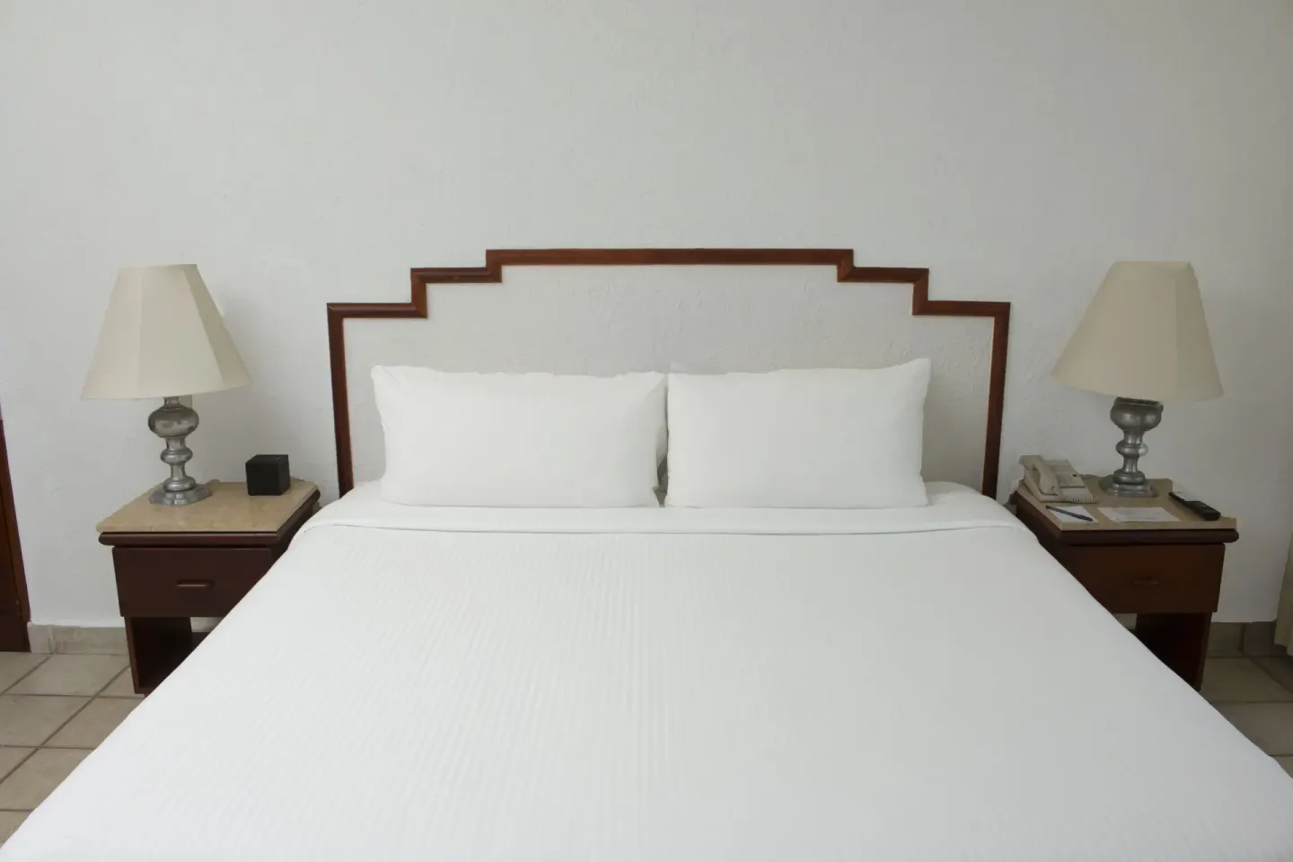 Junior Suite Ocean View king bed with bedside lamps at Emporio Ixtapa.