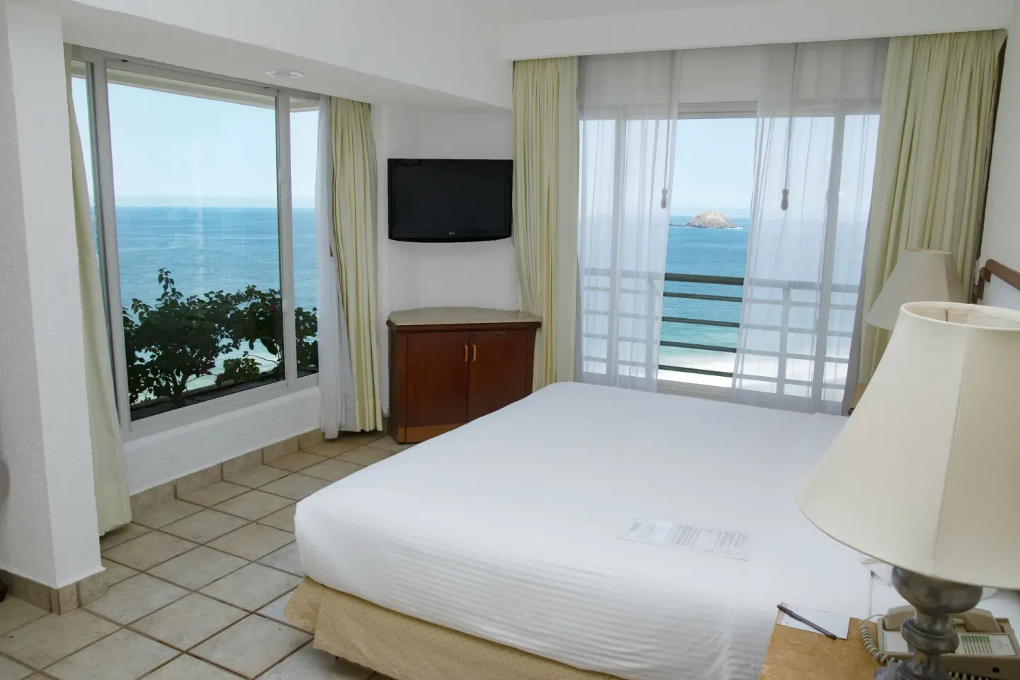 Junior Suite Ocean View bed beside windows facing the ocean at Emporio Ixtapa.