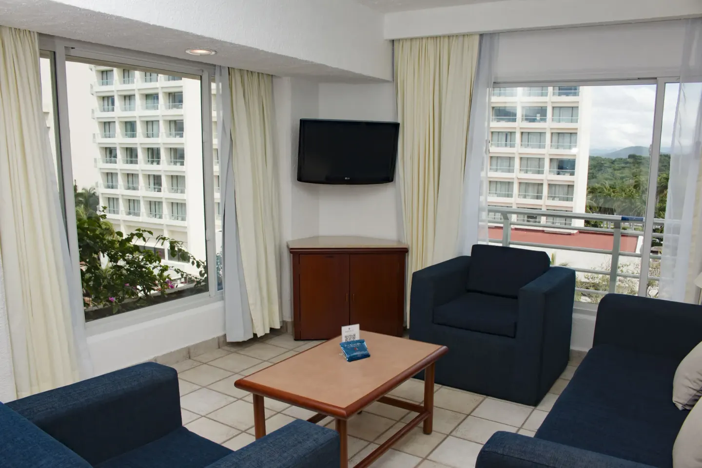 Junior Suite Ocean View sitting area with blue seating and windows at Emporio Ixtapa.