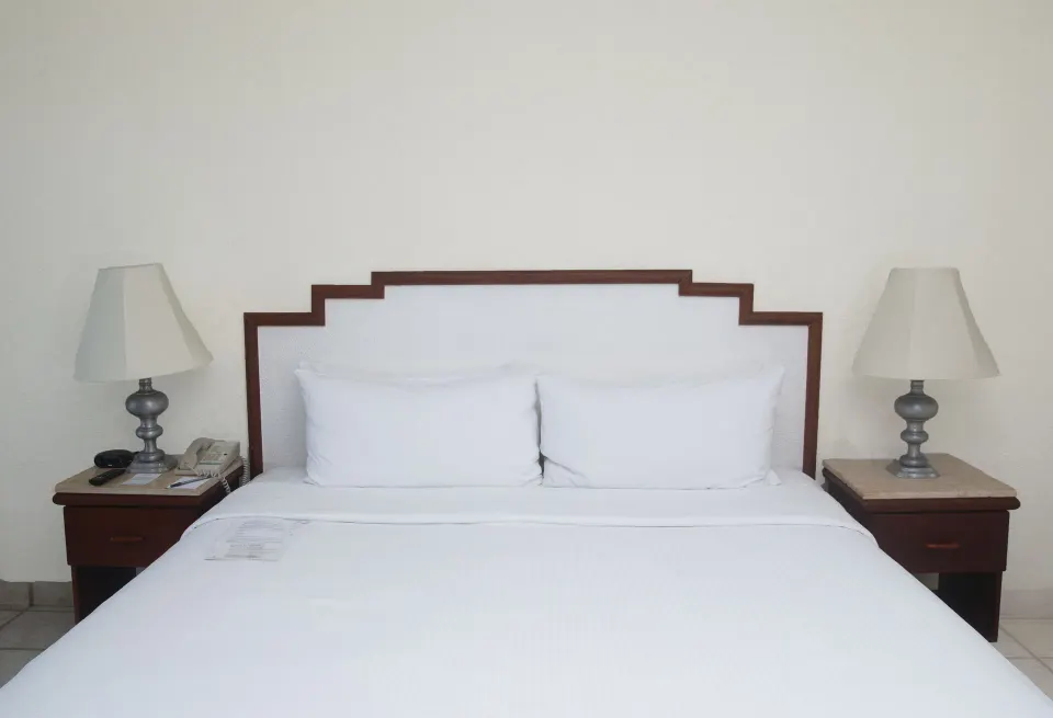 King bed with white bedding and lamps on both sides in a Superior Ocean View room at Emporio Ixtapa.