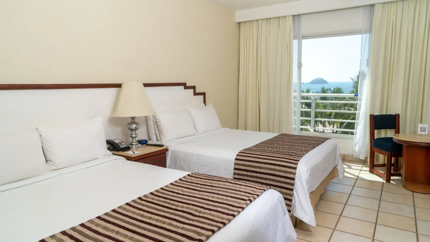 Two double beds in a Superior Ocean View room at Emporio Ixtapa with a balcony-style window view.