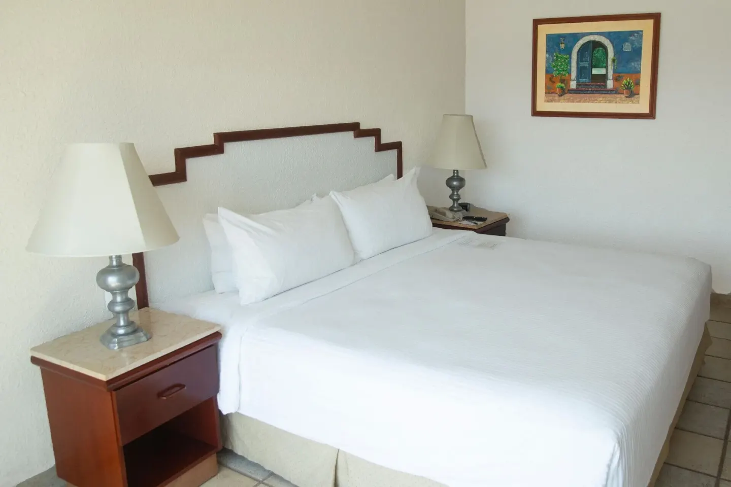 White bed with bedside lamps in a Superior Room Two Beds Mountain View at Emporio Ixtapa.