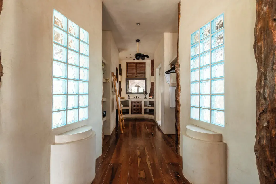 Long dressing corridor with glass block windows and a sink visible at the end at Encantada Tulum