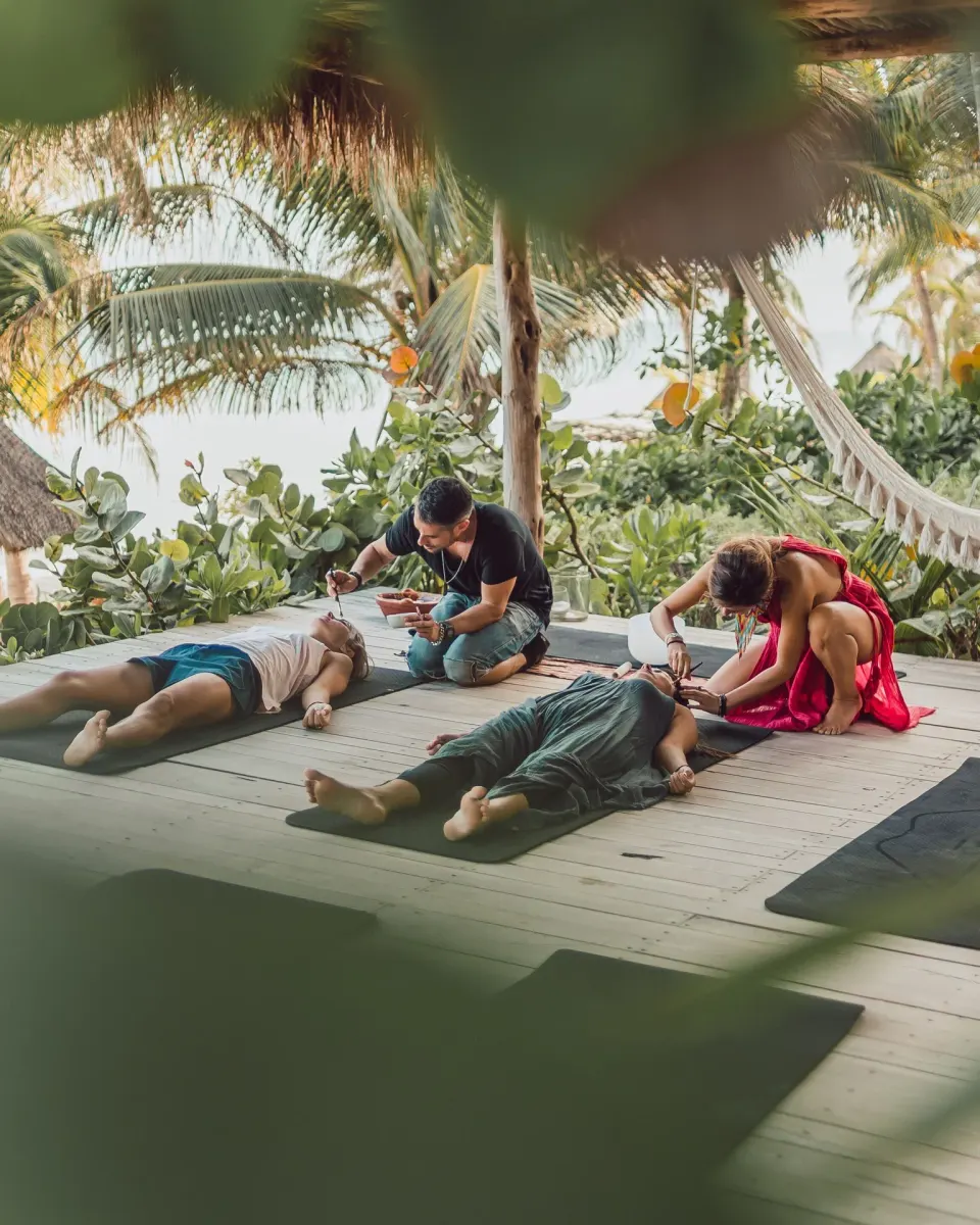 People receiving spa treatments while lying on mats on a wooden platform at Encantada Tulum