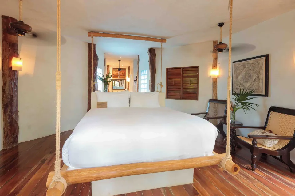Suspended bed on a wooden platform in a bright suite at Encantada Tulum