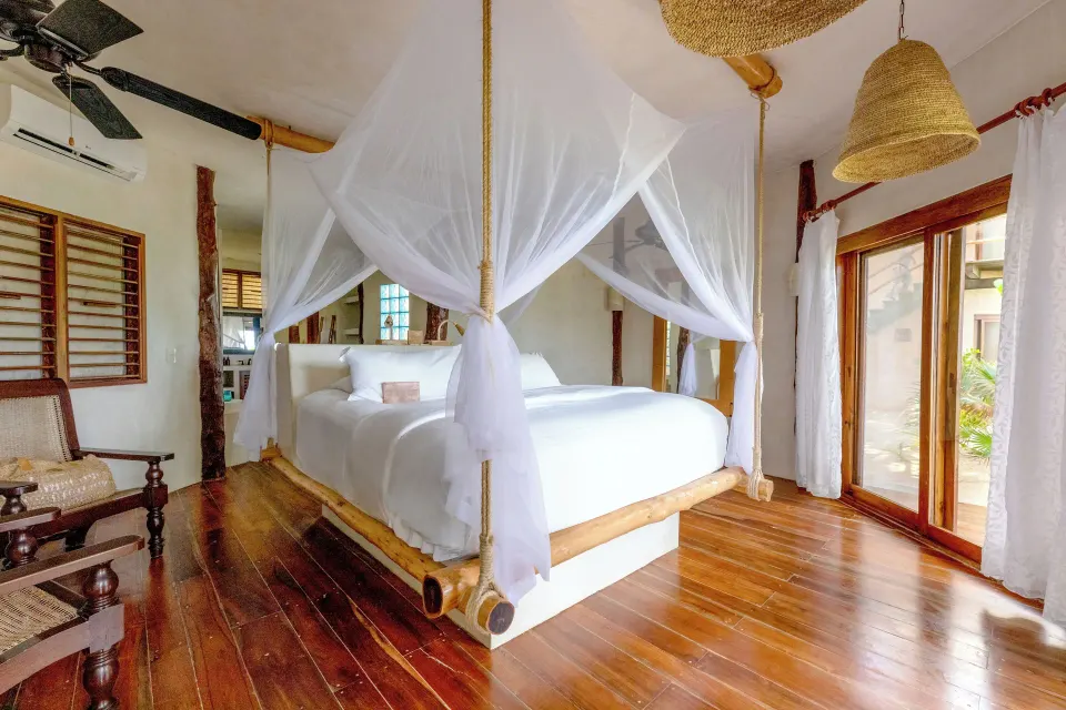 Bright bedroom with a four-poster king bed and wooden floors at Encantada Tulum