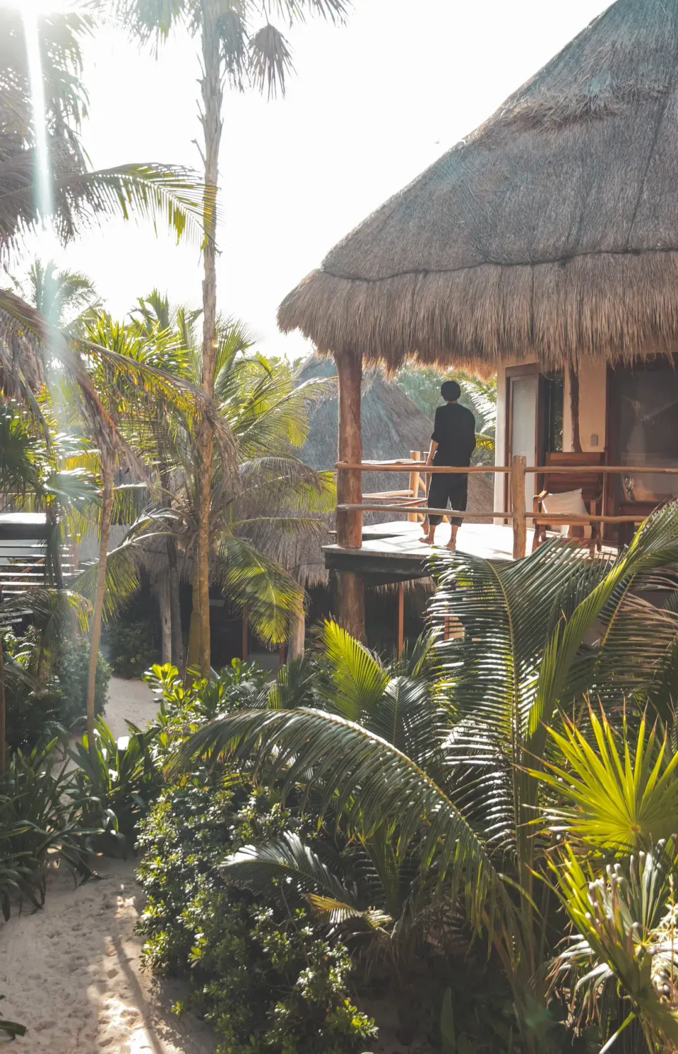 Raised palapa deck with a guest looking out among palms at Encantada Tulum
