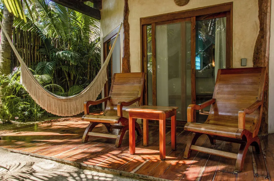 Two wooden lounge chairs and a hammock on a shaded patio at Encantada Tulum