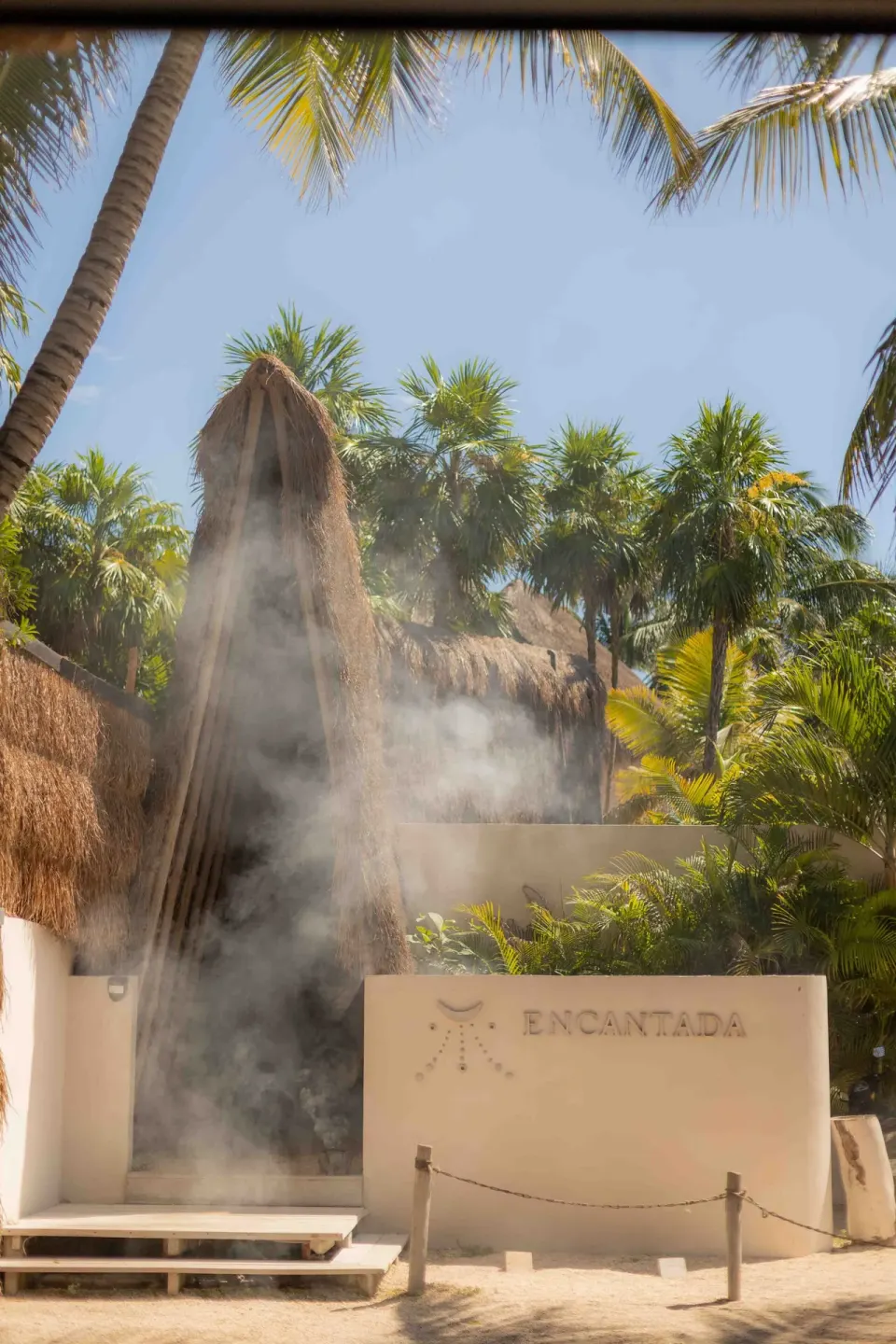 Outdoor entrance wall with Encantada sign and tropical steam at Encantada Tulum