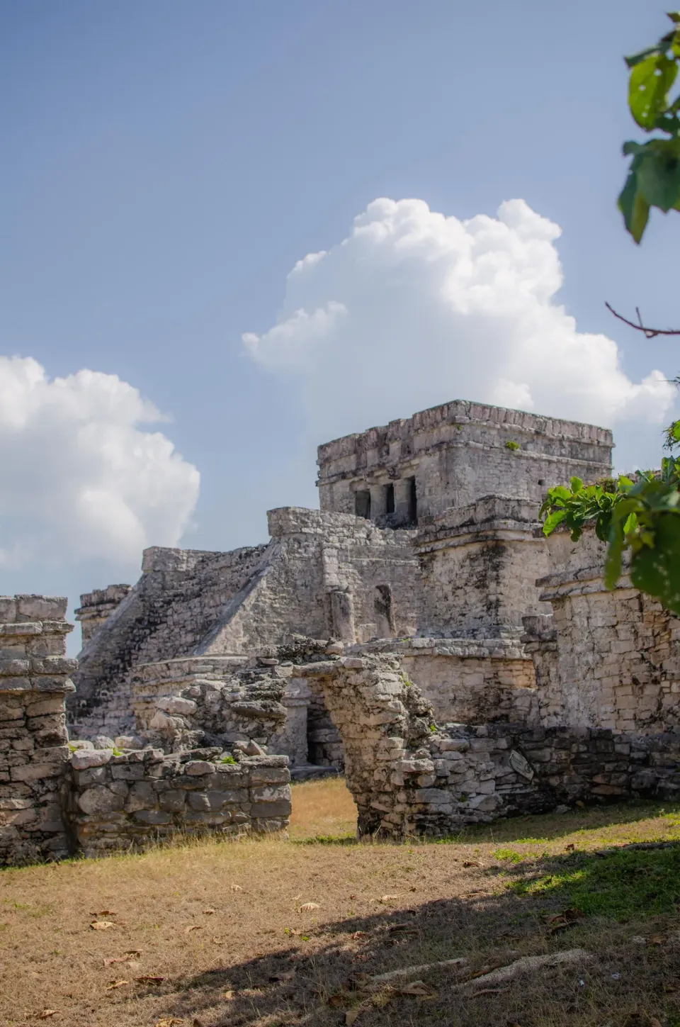 Historic stone temple ruins framed by blue sky and clouds at Encantada Tulum.