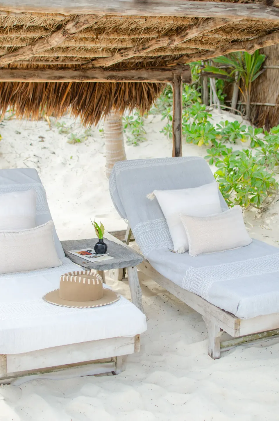 Two loungers under a palapa on the sand facing the ocean at Encantada Tulum