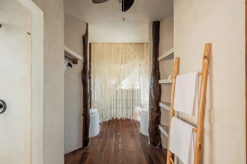 Walkway between two open shower or closet niches with a beaded curtain at the far end at Encantada Tulum