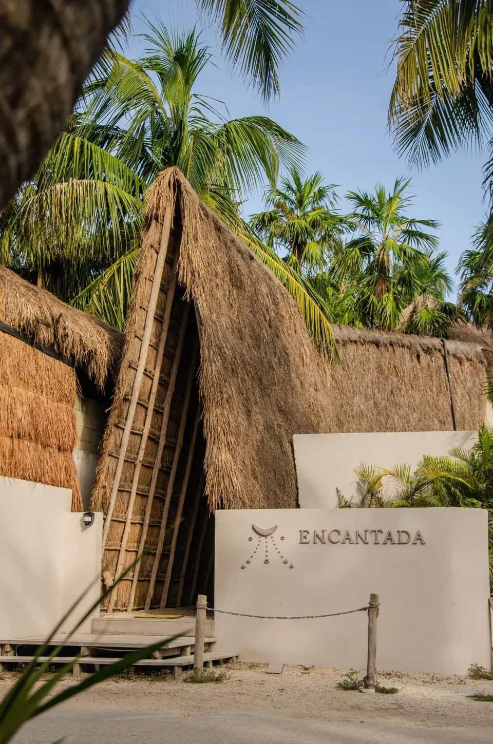 Thatched entry structure with resort name on a wall at Encantada Tulum