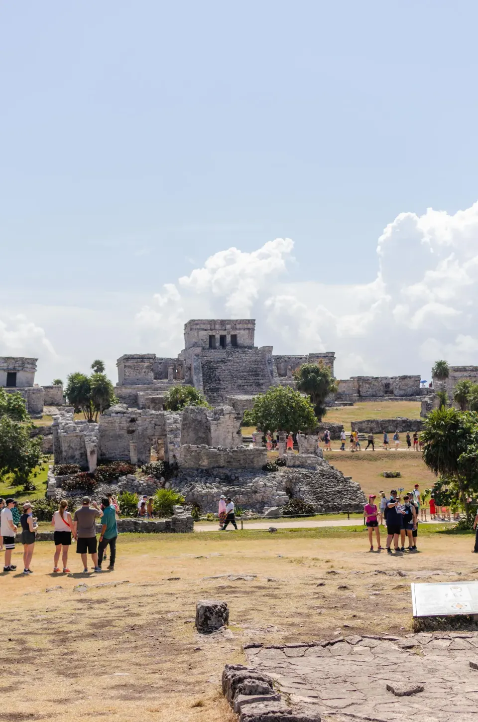 Ancient stone ruins and visitors on the grounds near Encantada Tulum under a blue sky