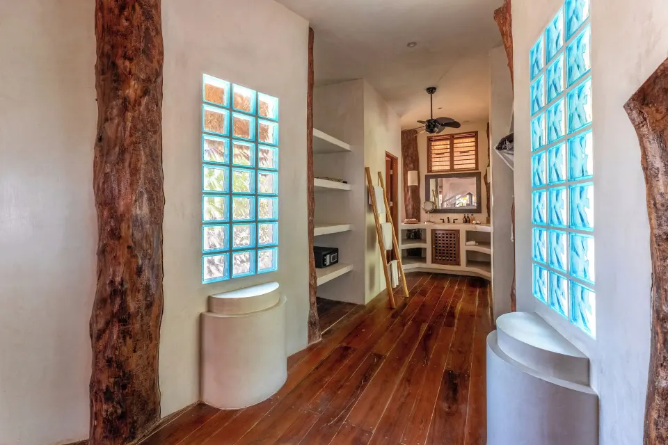 Dressing hall with glass block windows, shelving and a vanity at Encantada Tulum
