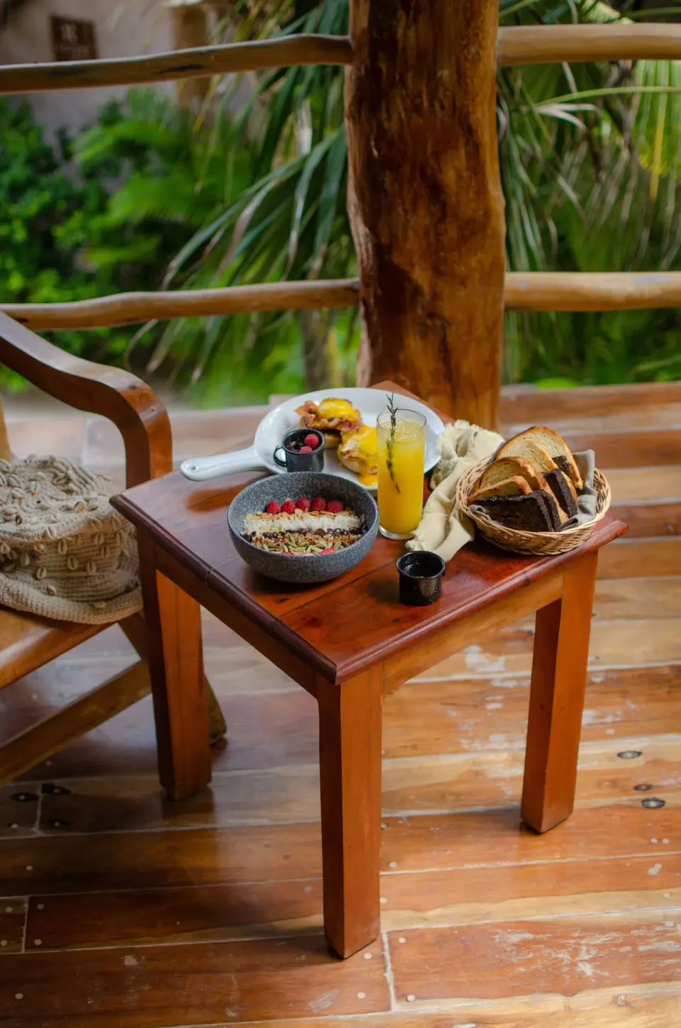 Breakfast spread with granola bowl, fruit and juice on a balcony table at Encantada Tulum.
