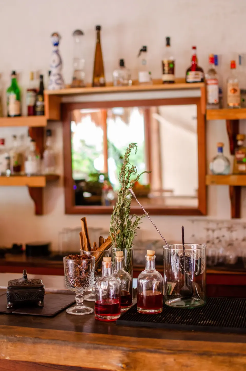 Bar counter with bottles, glassware and cocktail ingredients at Encantada Tulum.
