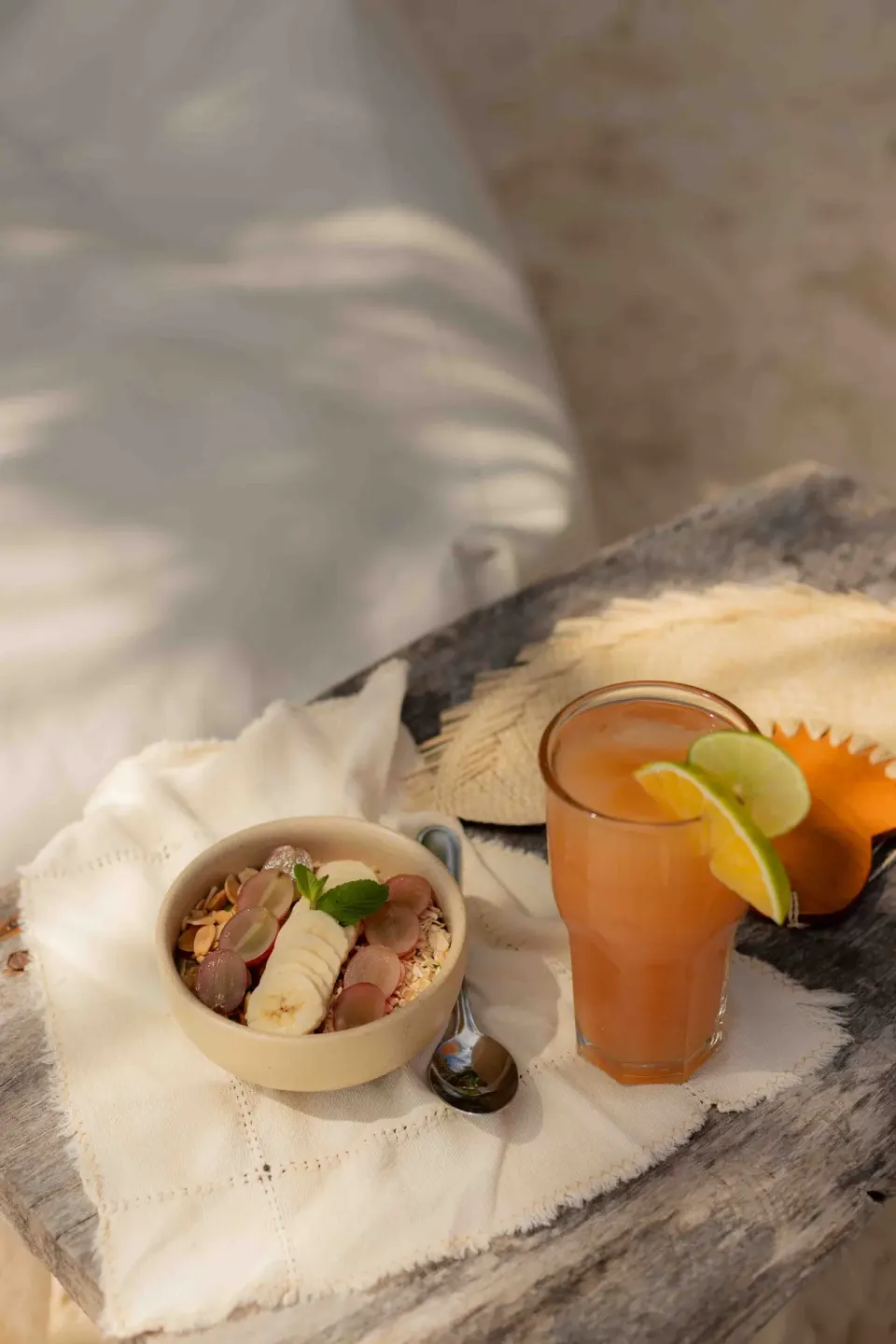 Breakfast bowl and glass of juice on a wooden table at Encantada Tulum beach