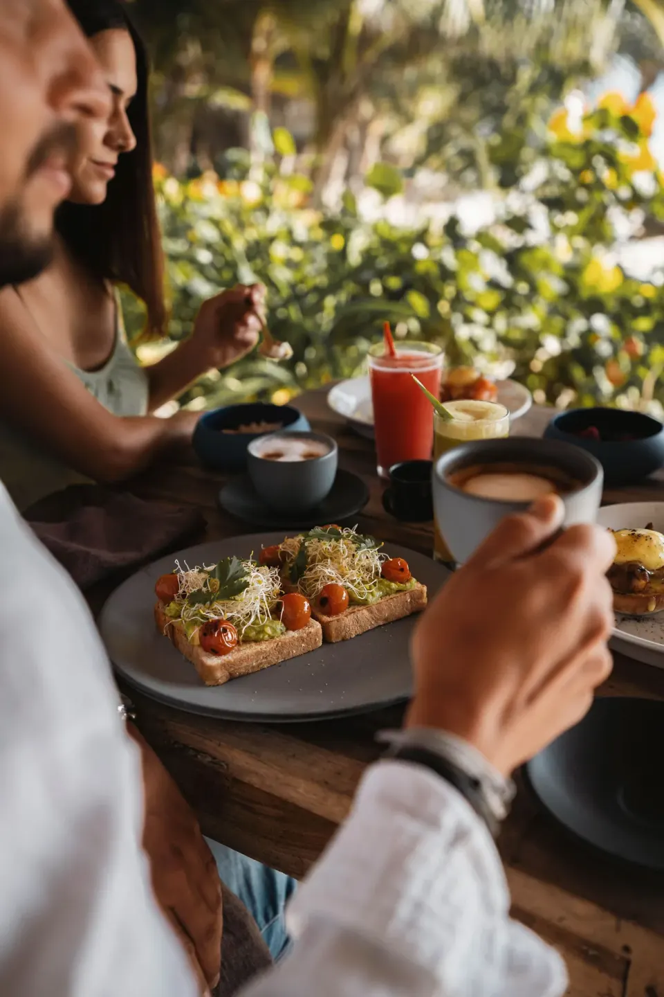Couple enjoying a beachfront breakfast with coffee and toast at Encantada Tulum