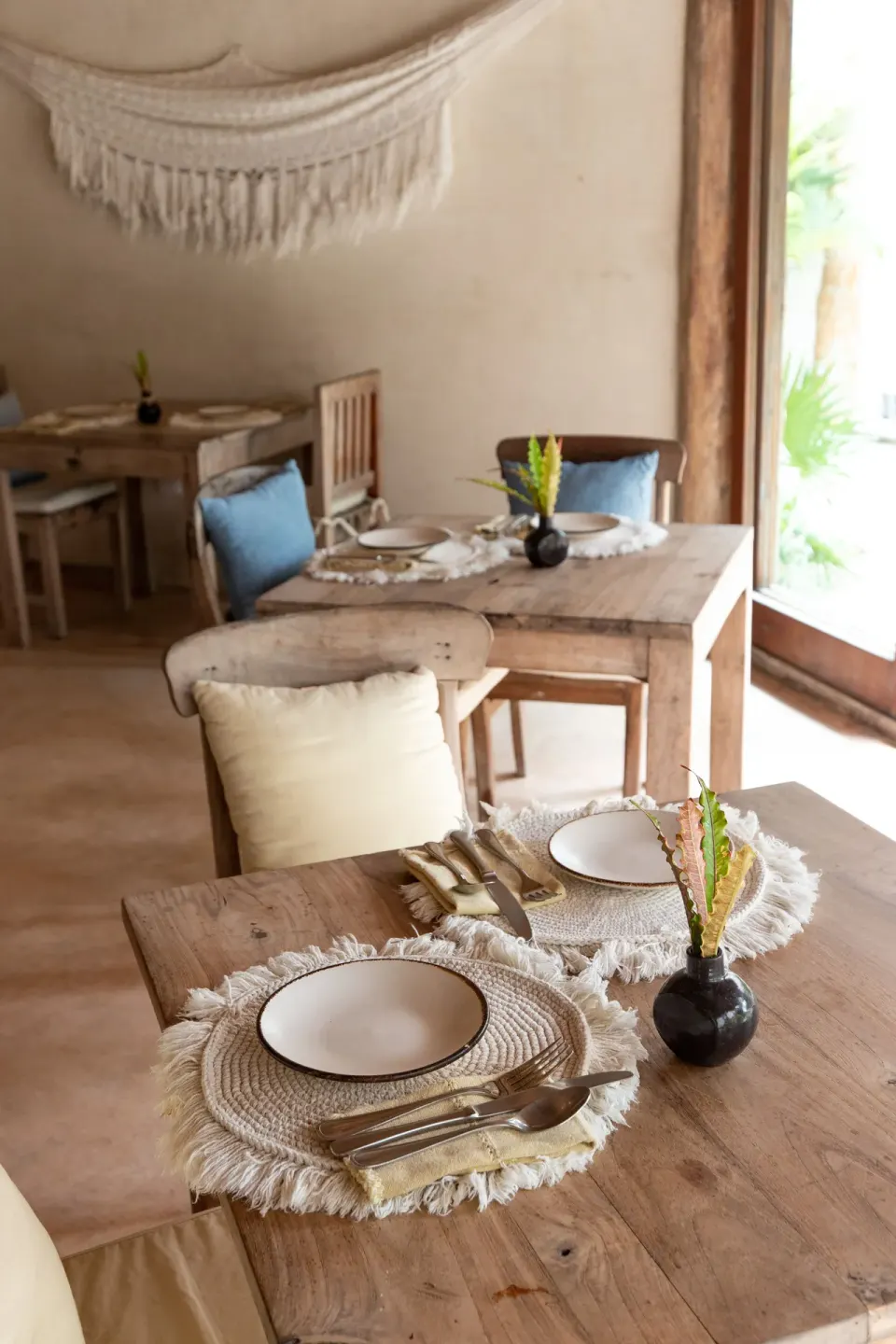 Light-filled dining table set for two with woven placemats at Encantada Tulum.