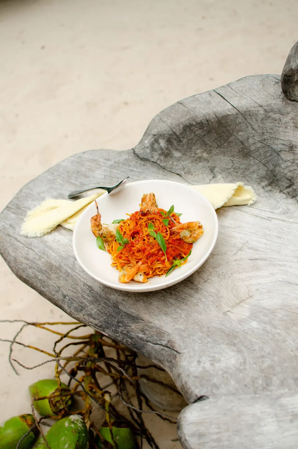 Bowl of noodle dish served on a carved wooden surface at Encantada Tulum.