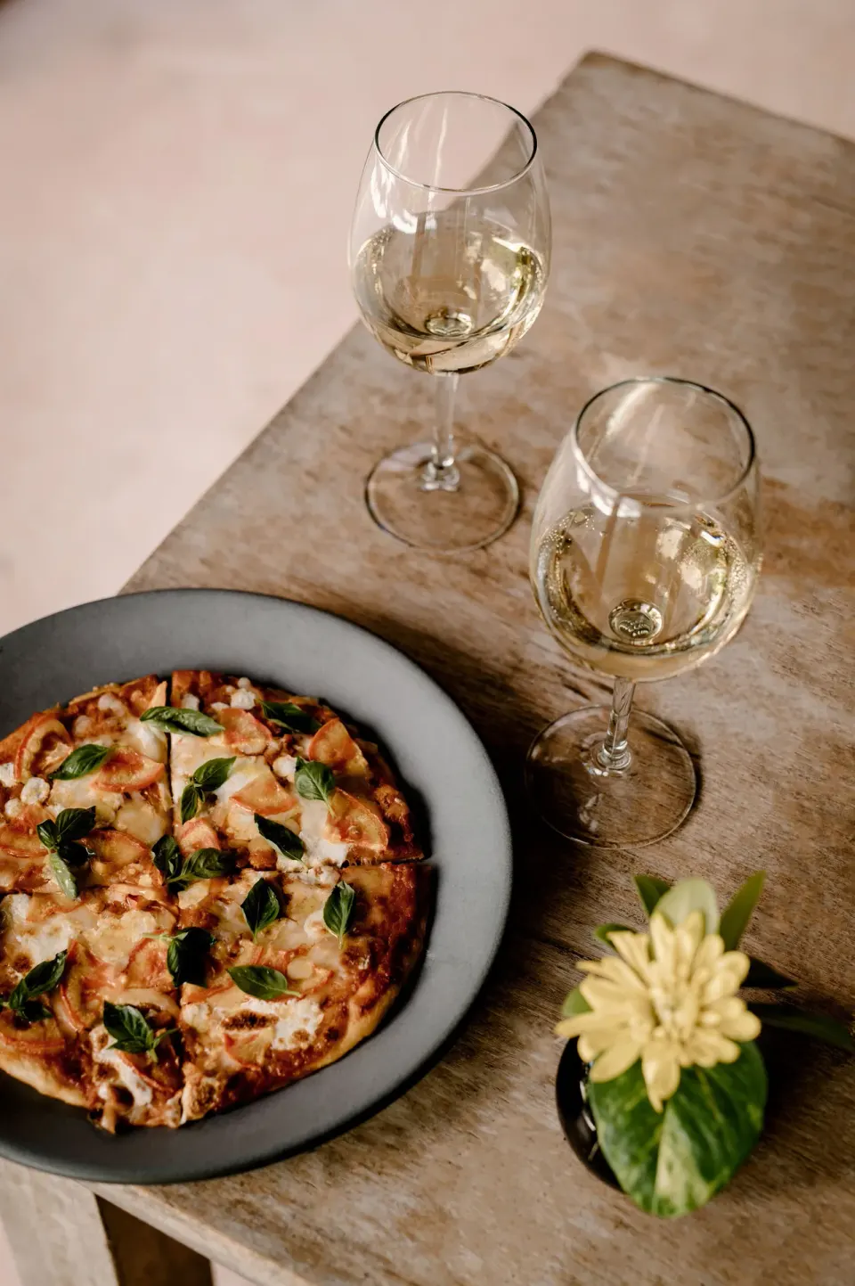 Pizza and two glasses of white wine on a table at Encantada Tulum.