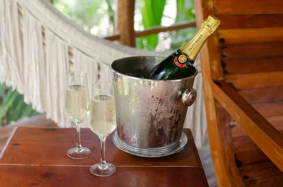 Chilled bottle of sparkling wine in an ice bucket with two flute glasses at Encantada Tulum.