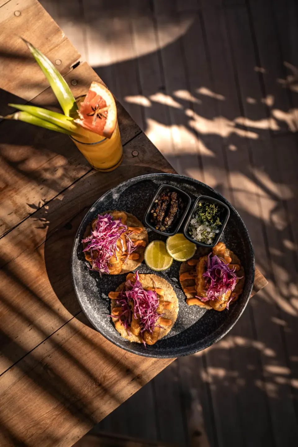 Top-down view of three tostadas with pickled cabbage and lime at Encantada Tulum