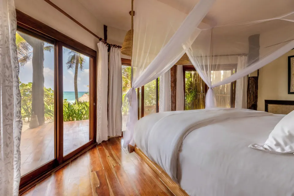 Canopy king bed and sliding glass doors looking toward the beach at Encantada Tulum