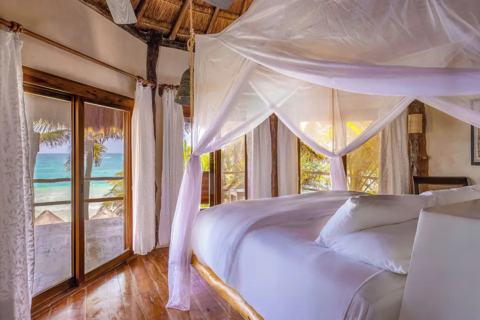 Canopied king bed and ocean view from the Beach Front Upper Room at Encantada Tulum