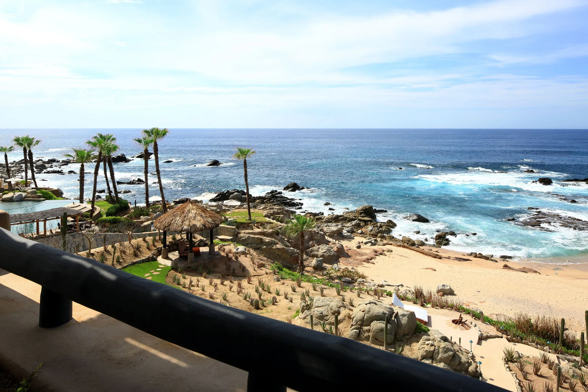 Balcony view over palms, beach, rocks, and the ocean at Esperanza.