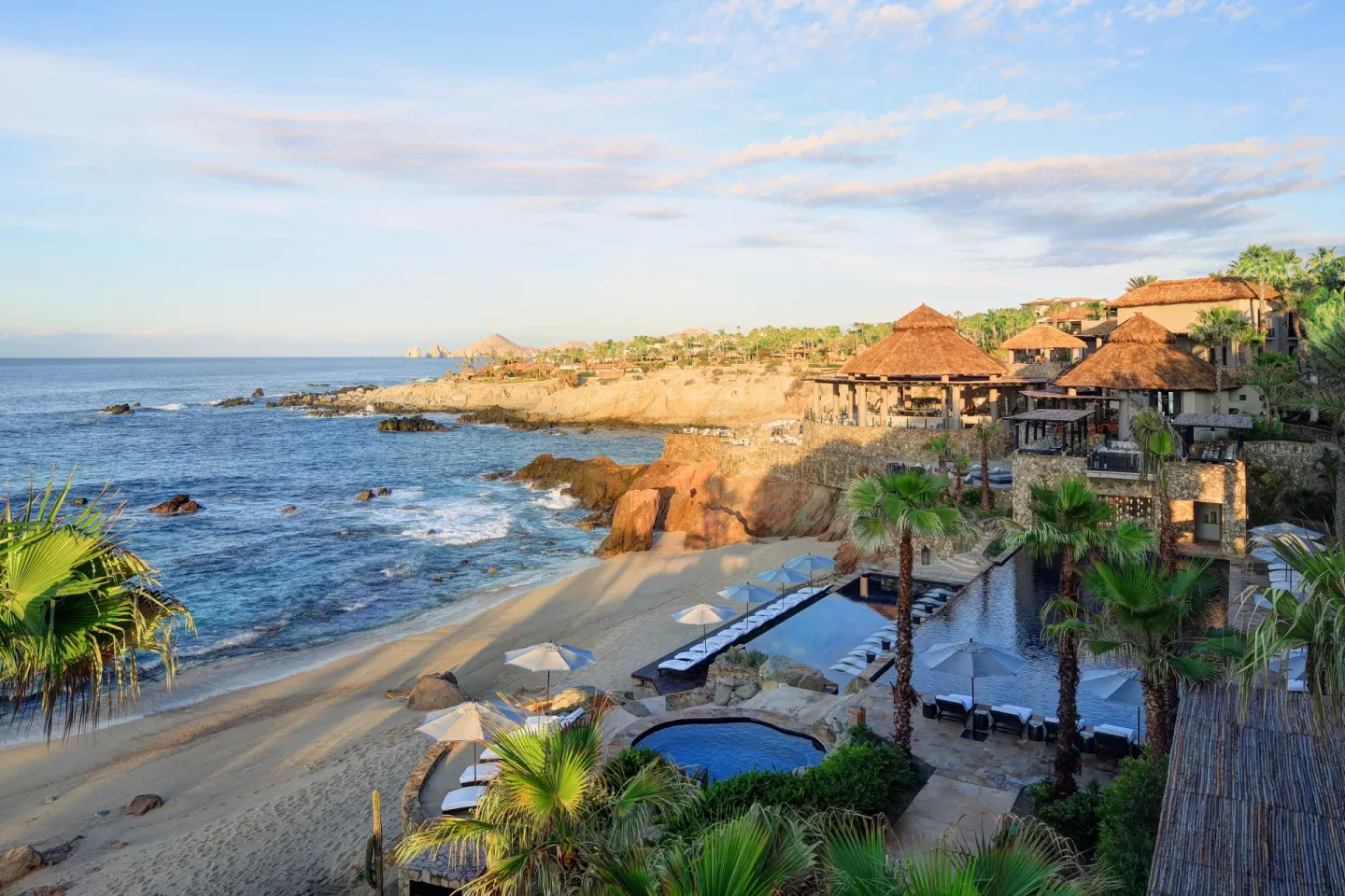 Beach, pools, palms, and cliffside thatched-roof buildings at Esperanza.
