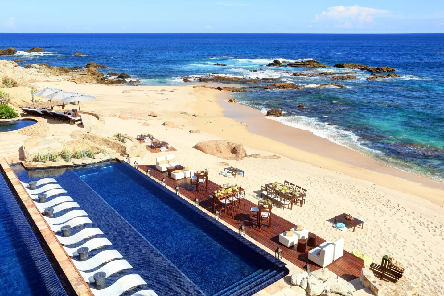 Beachfront pool, deck seating, and rocky blue shoreline at Esperanza.