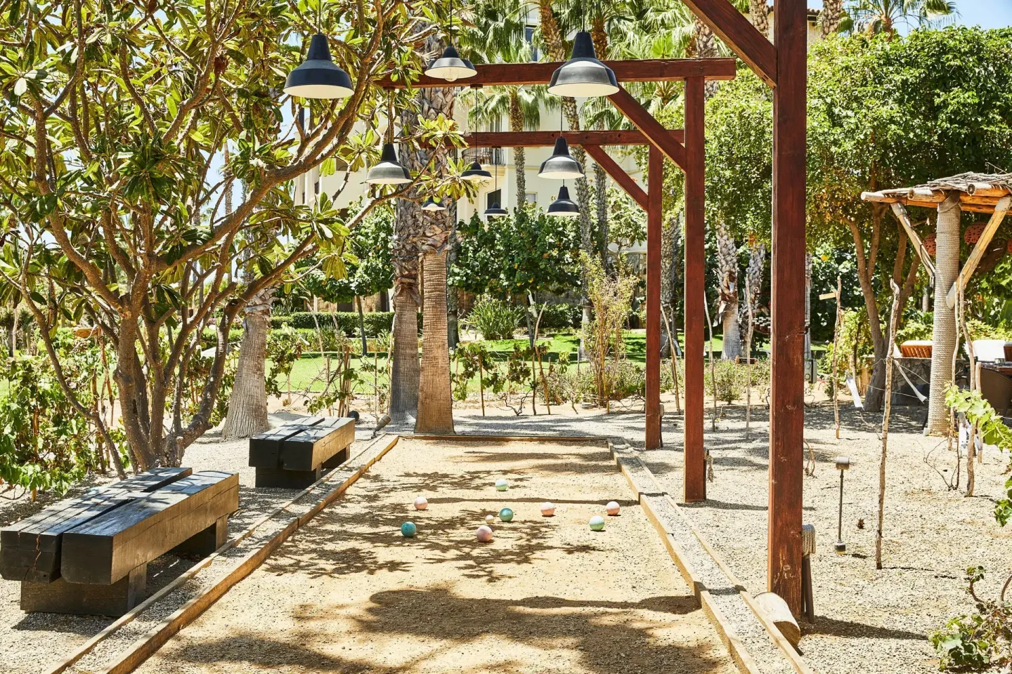 Shaded bocce court with benches and hanging lights in the gardens at Esperanza.