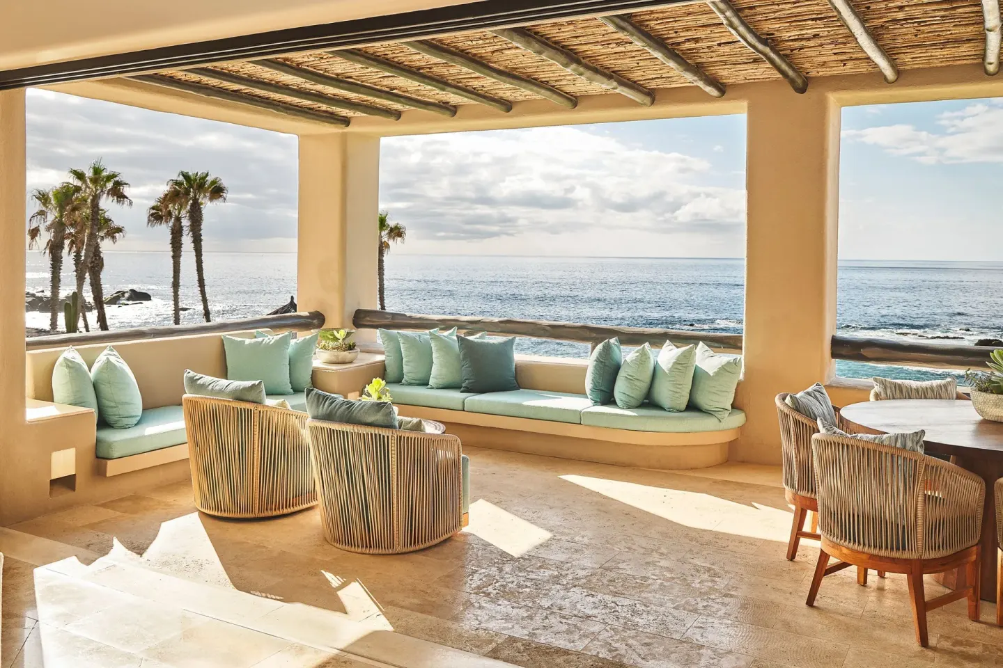 Covered ocean-view terrace with cushioned seating and woven chairs at Esperanza.