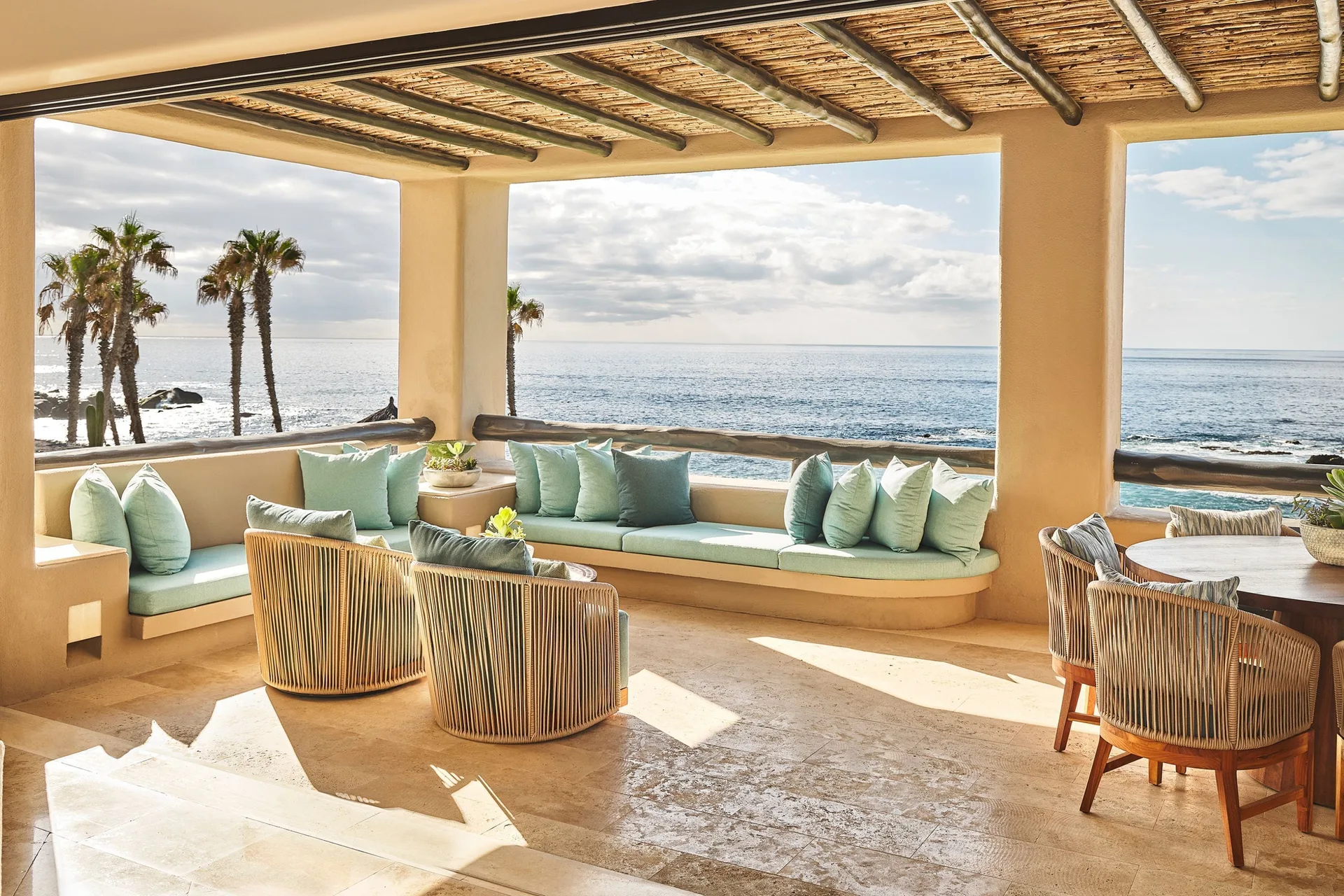 Covered ocean-view terrace with cushioned seating and woven chairs at Esperanza.